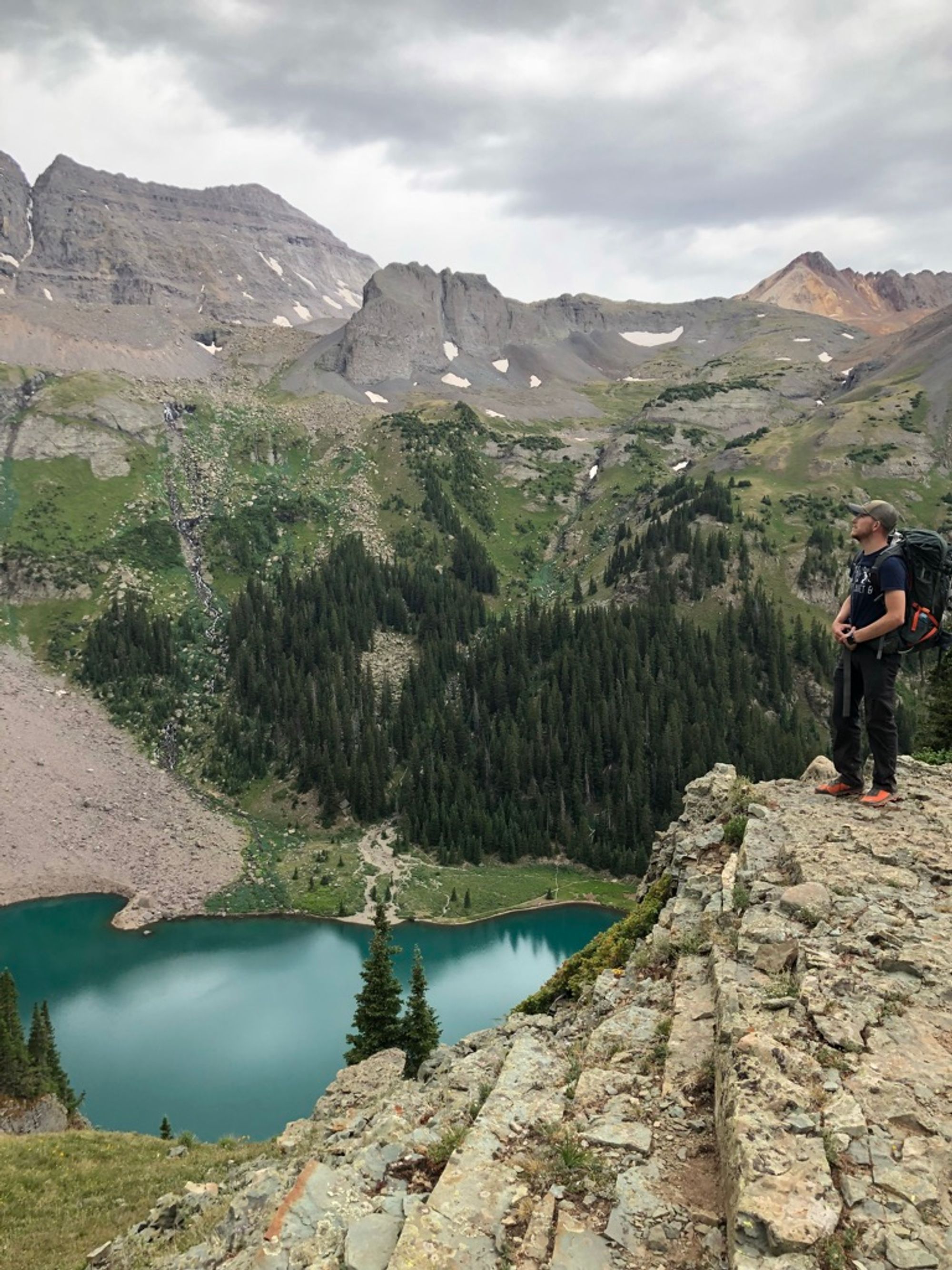 Me, on a cliff, overlooking a Blue Lake and the towering ridgeline above